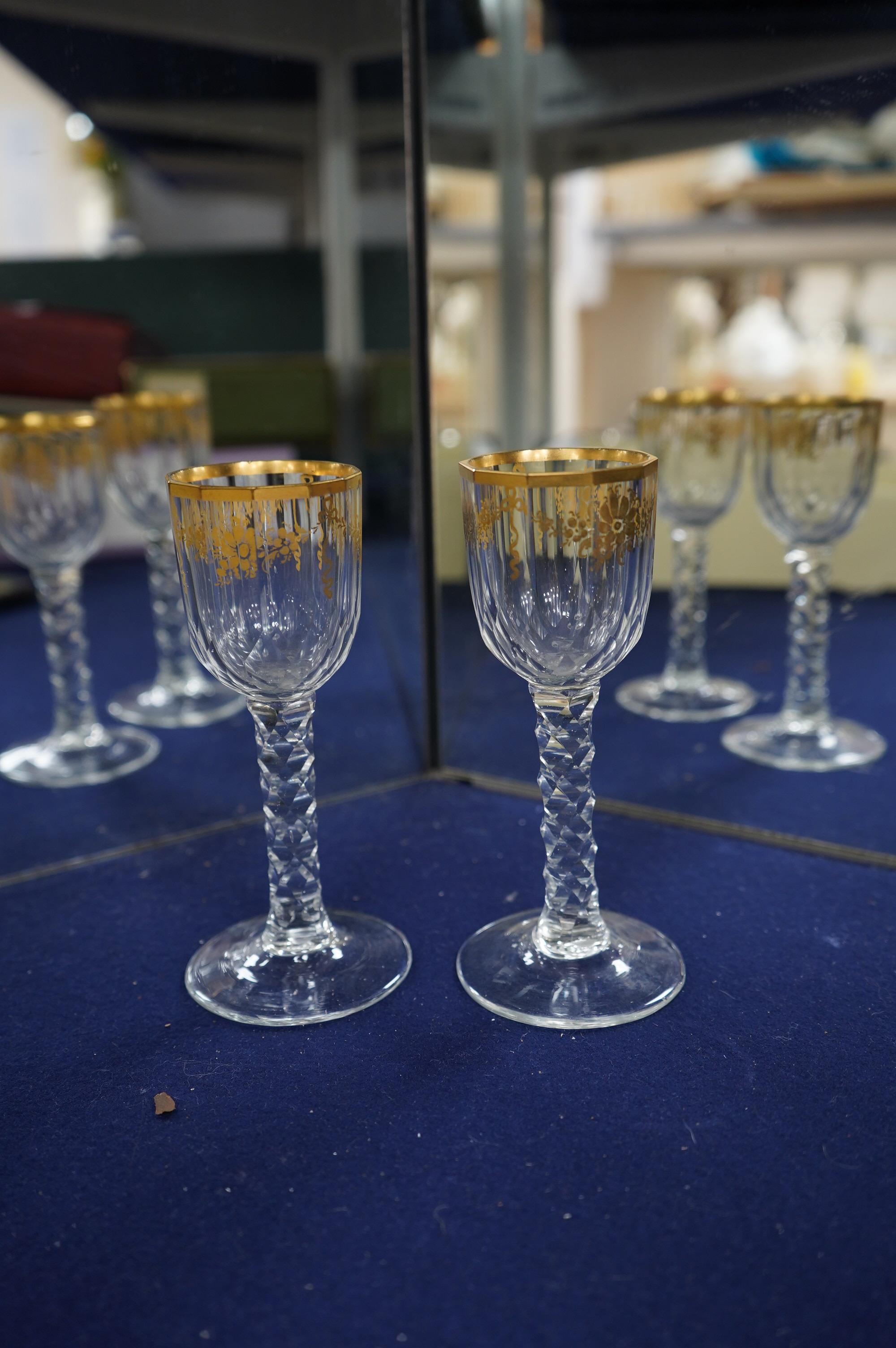 A pair of early 18th century octagonal glasses with gilt floral swagged decoration and facetted stems. Condition - slight wear to gilding otherwise good